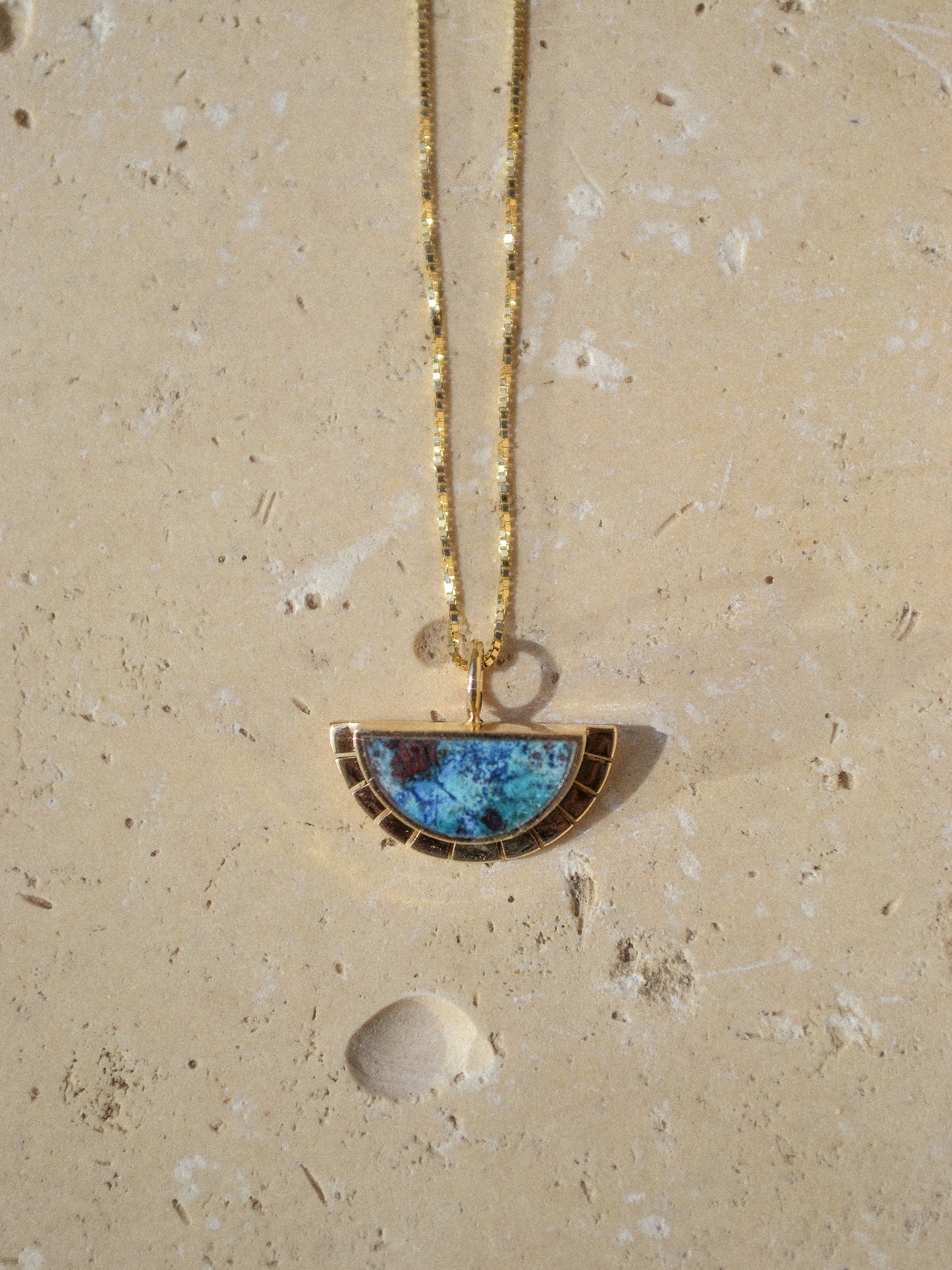 young in the mountains / half circle of warm 14k yellow gold is wrapped around an inlaid Shattuckite stone while a serrated halo of light radiates from this sun. This pendant hangs freely on a 14k yellow gold box chain