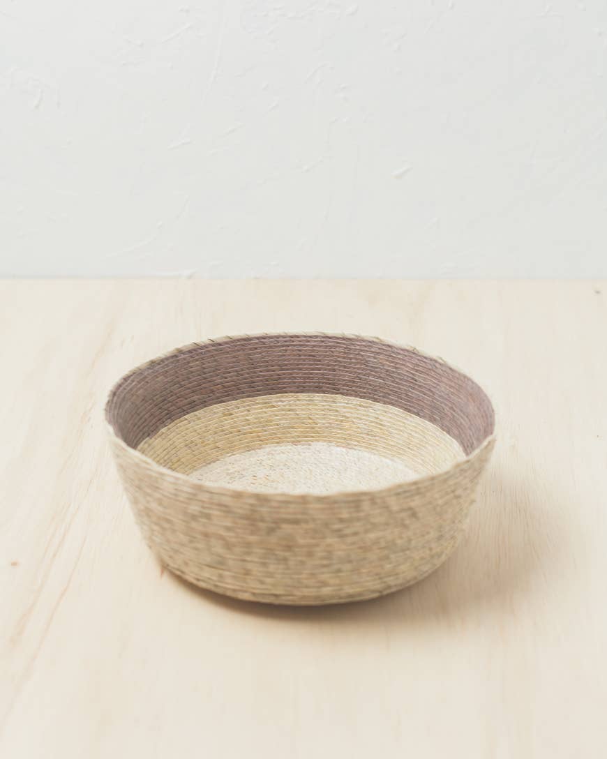 In the mountains of Southern Mexico, artisans weave these exquisite baskets from sun-dried palm leaves. Each takes days to complete using traditional skills passed down through generations. This versatile design pairs the beautiful hues of natural fiber with a block of subtle earthy color.