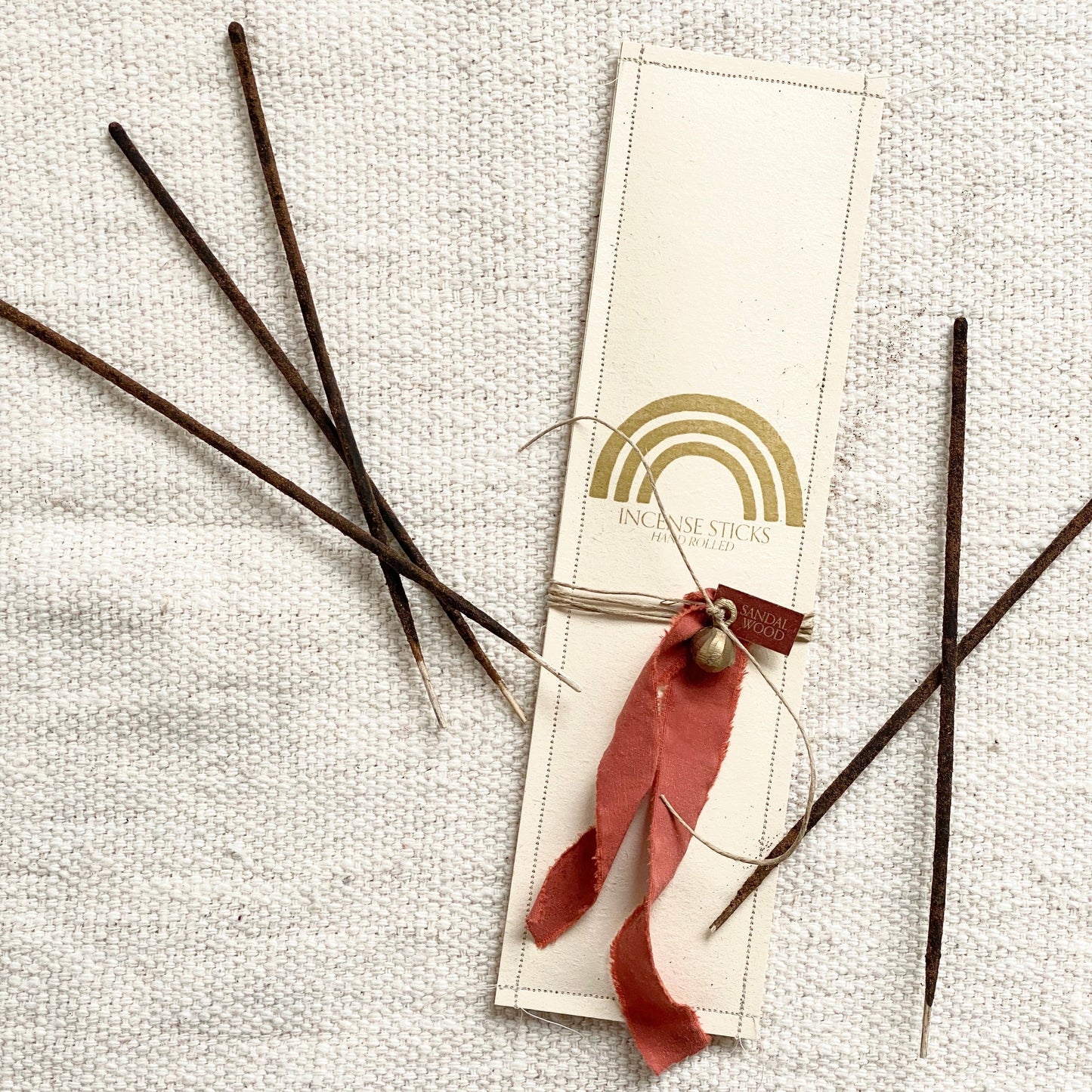 Pack of 12 hand rolled, sandalwood incense sticks Each pack is wrapped with hemp, vintage fabric, and a brass bell. by catherine rising