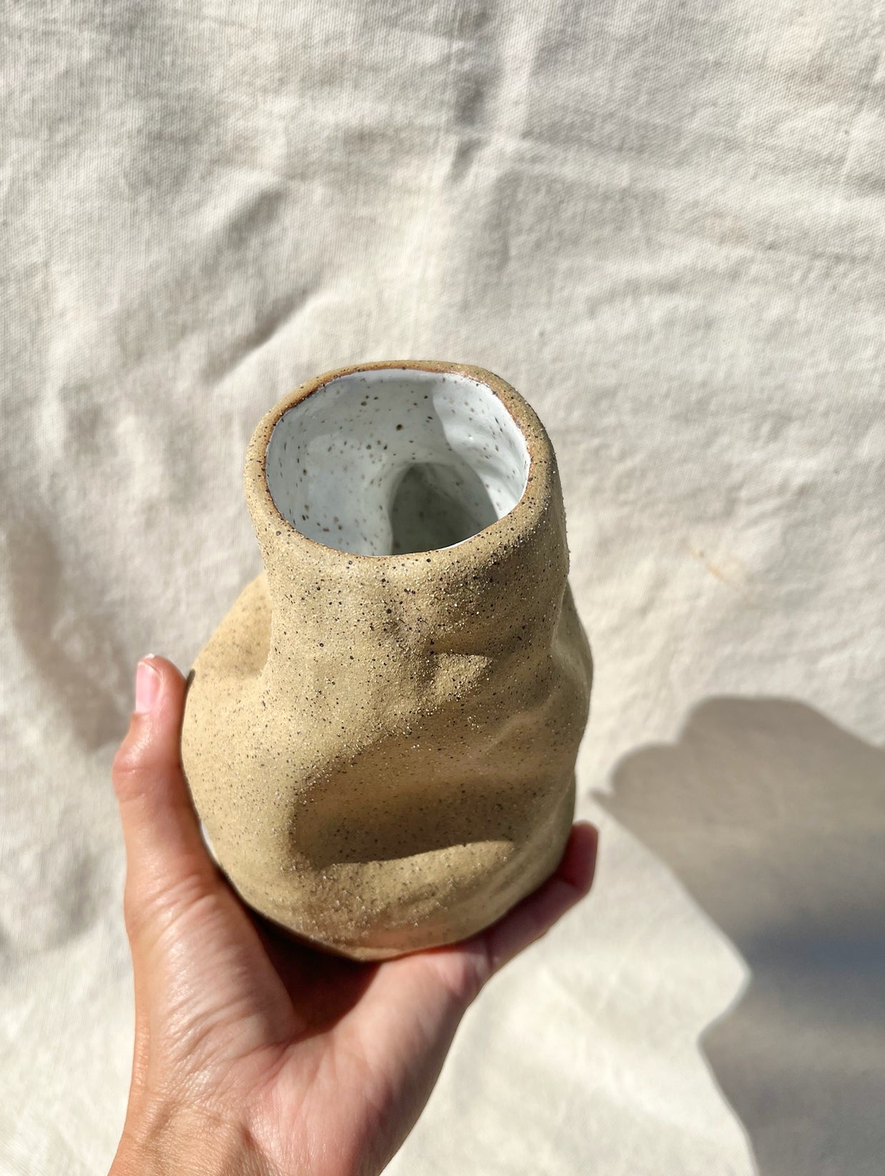An organic vase with a speckled, textured clay body and white glaze on the inside. A vase for your fresh or dried flowers, yes… but also an alcove to place a teeny treasure to compliment them. Hand built, glazed and fired in Slo, Ca.
