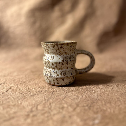 Speckled ceramic mug on a textured brown surface