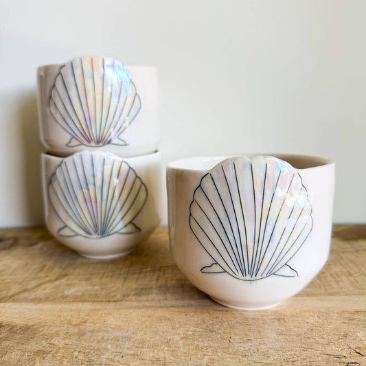 Seashell cups are hand-thrown from fine porcelain, and feature hand drawn inlay and mother of pearl luster for a delicate and iridescent shine.