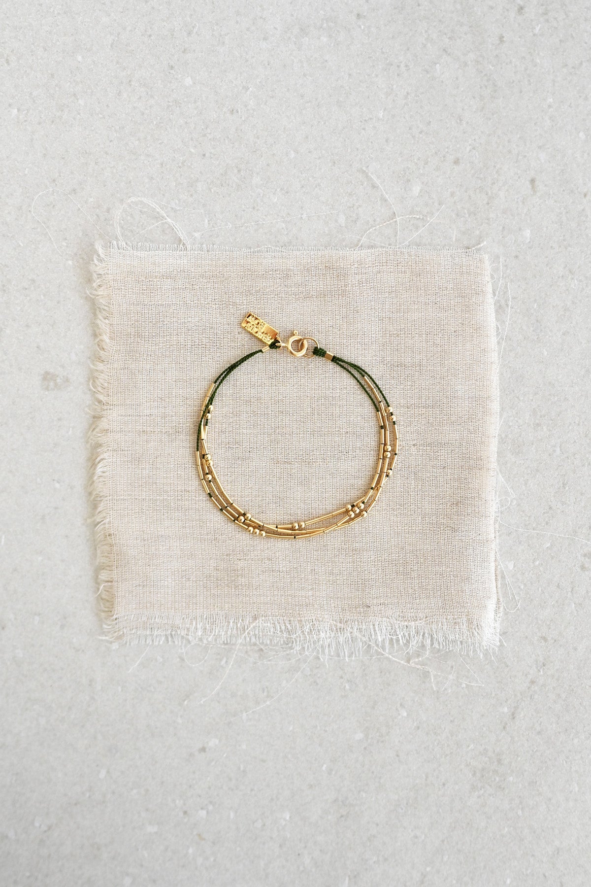 A refined and effortless bracelet designed to elevate your day-to-day. The Ara is a triple-stranded silk cord bracelet stacked with gold tubes and rounds that shift freely.