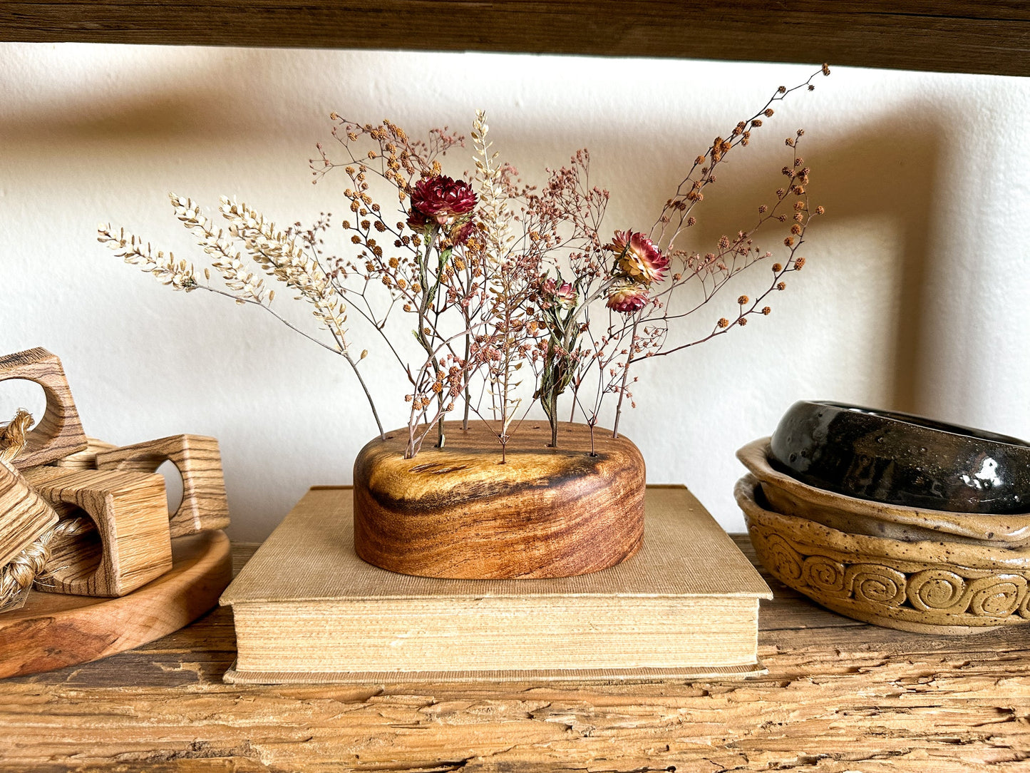 A wooden flower frog made from reclaimed mesquite. These were designed to provide a hint of warmth while giving you the creative play on height, color, texture and "flow" for your florals.