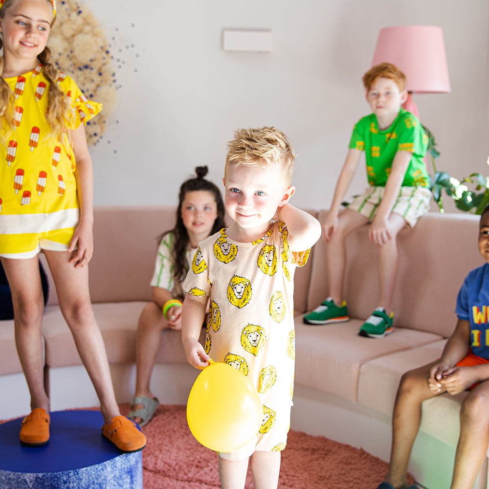 Tan romper with a playful lion print. Short sleeves & legs for play, and snap buttons for easy changing.  Ethically produced, colorful and fun with an eye towards comfort, style and joy. Modern and sustainable kids clothing by CarlijnQ of the Netherlands.