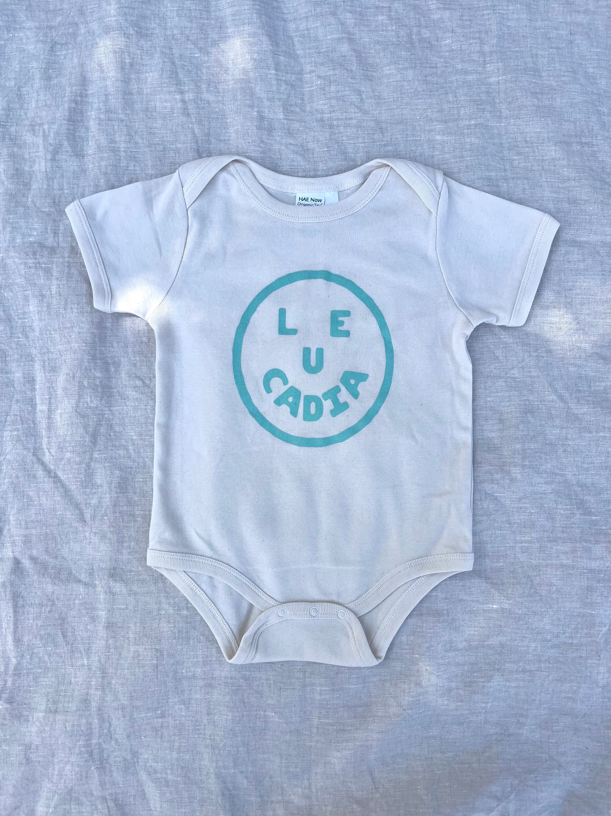 A fun little organic infant onesie with a super cute little Leucadia smiley face by local artist Zach Smith. Printed on an organic cotton, fair trade onesie with all proceeds to San Diego area families facing housing insecurity. Keep it funky, keep it kind, keep it local.