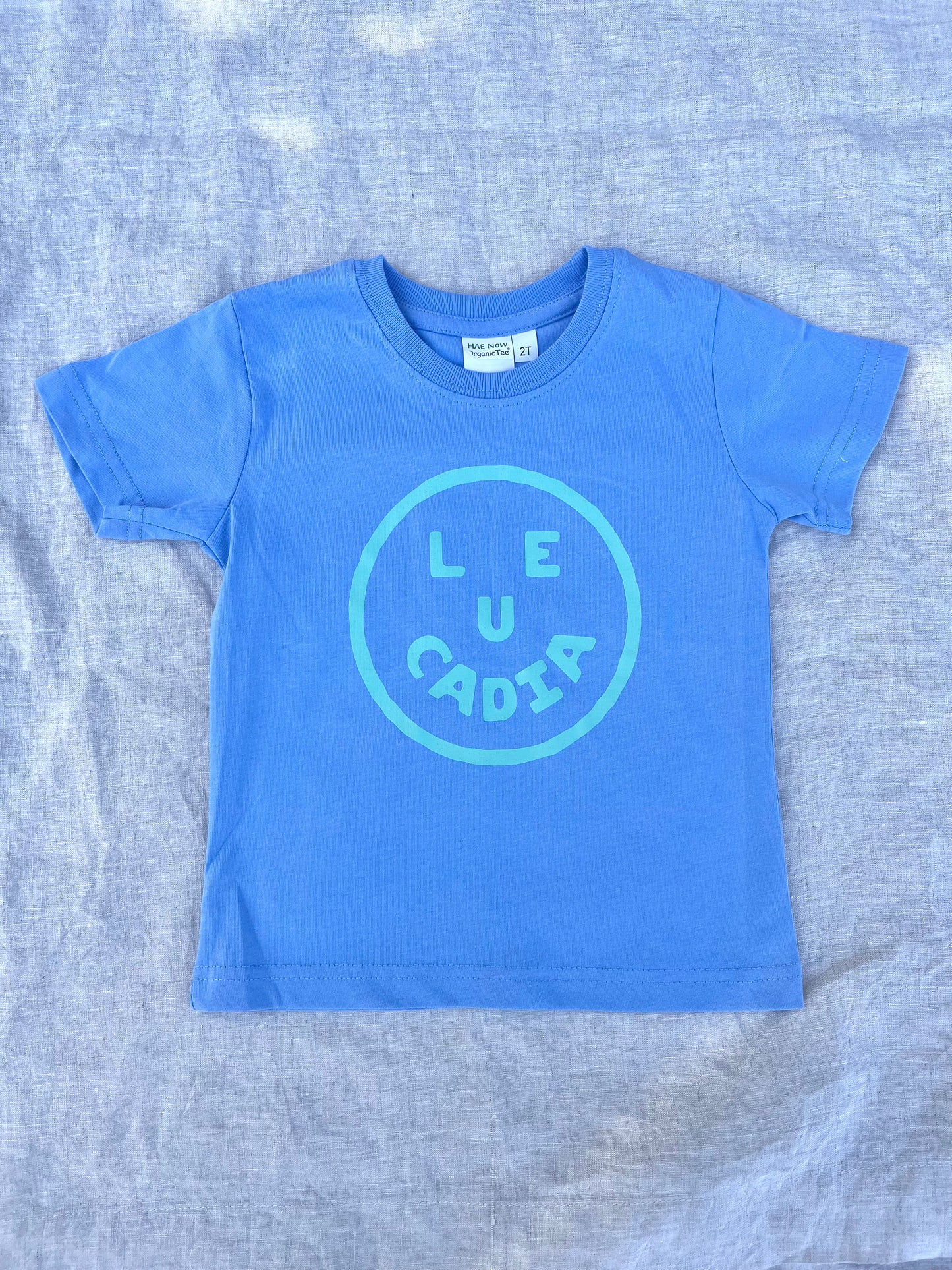 A fun little organic kids tee with a super cute little Leucadia smiley face by local artist Zach Smith. Printed on an organic cotton, fair trade tee with all proceeds to San Diego area families facing housing insecurity. Keep it funky, keep it kind, keep it local.
