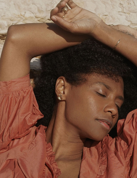 Woman in a pink top with her eyes closed, wearing gold earrings and a ring. Amanda Hunt Vita Earrings