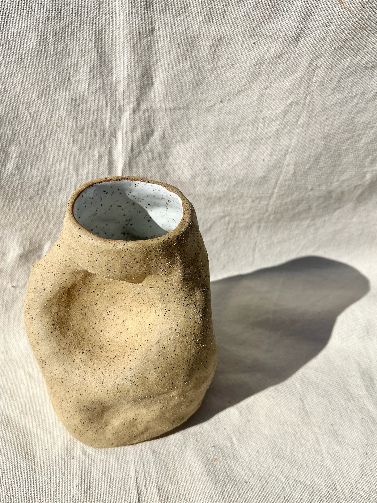 An organic vase with a speckled, textured clay body and white glaze on the inside. A vase for your fresh or dried flowers, yes… but also an alcove to place a teeny treasure to compliment them. Hand built, glazed and fired in Slo, Ca.