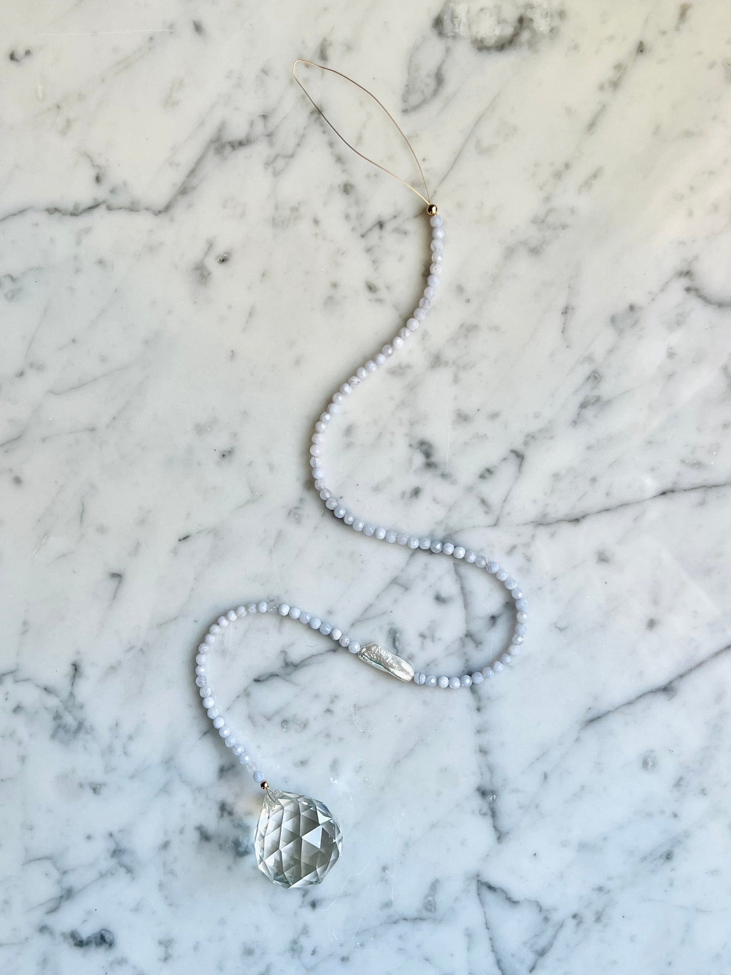 Adorn your space with a window prism - hang in a sunny spot & watch the rainbows dance! In need of a little peace & quiet? Blue Lace Agate & Pearl pair washes away tense energies & pulls in tides of relief & tranquility. Designed in California by Carrie Marill.