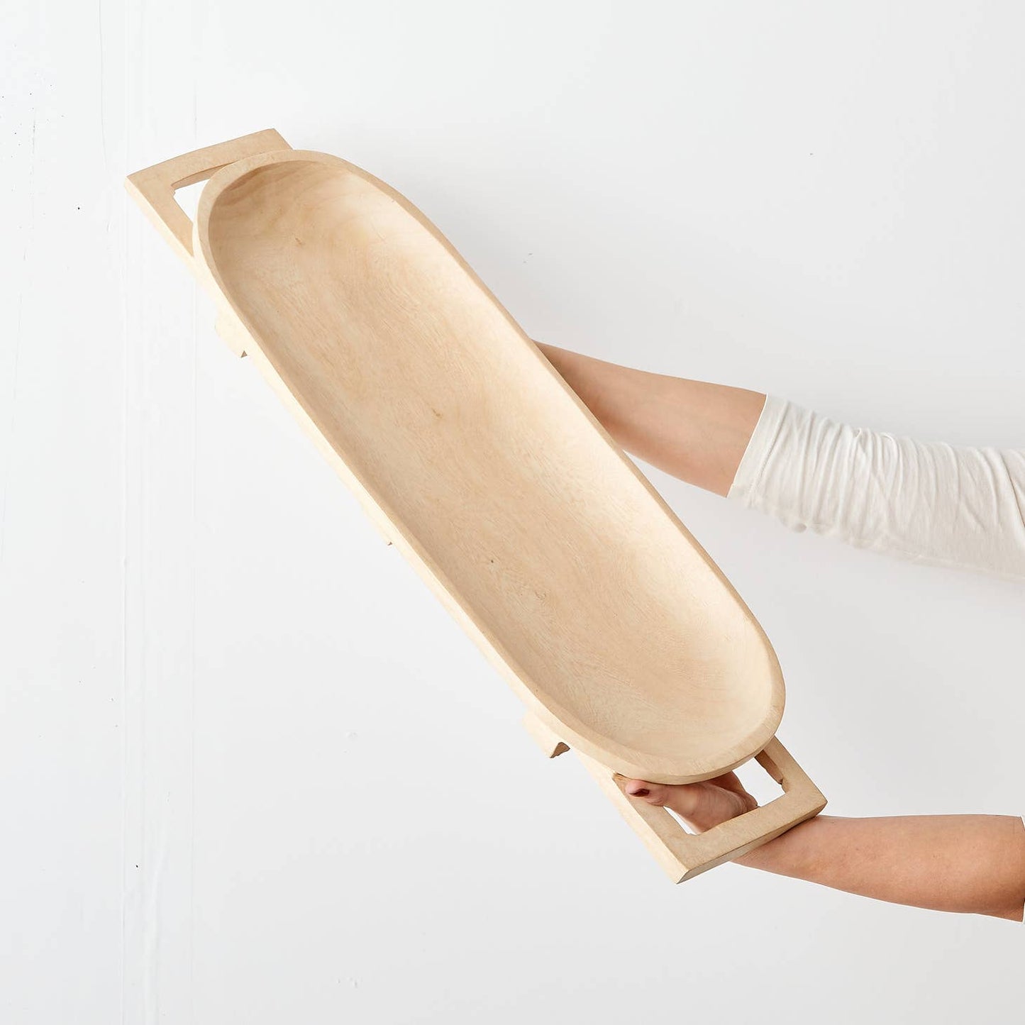 These elegant, raised long trays are hand carved in Eswatini from sustainably sourced Jacaranda wood, a form of rosewood that is very common throughout southeast Africa. They are carved from a single piece of wood, including the legs and handles, and polished to a natural sheen, available in a raw, light wood finish.