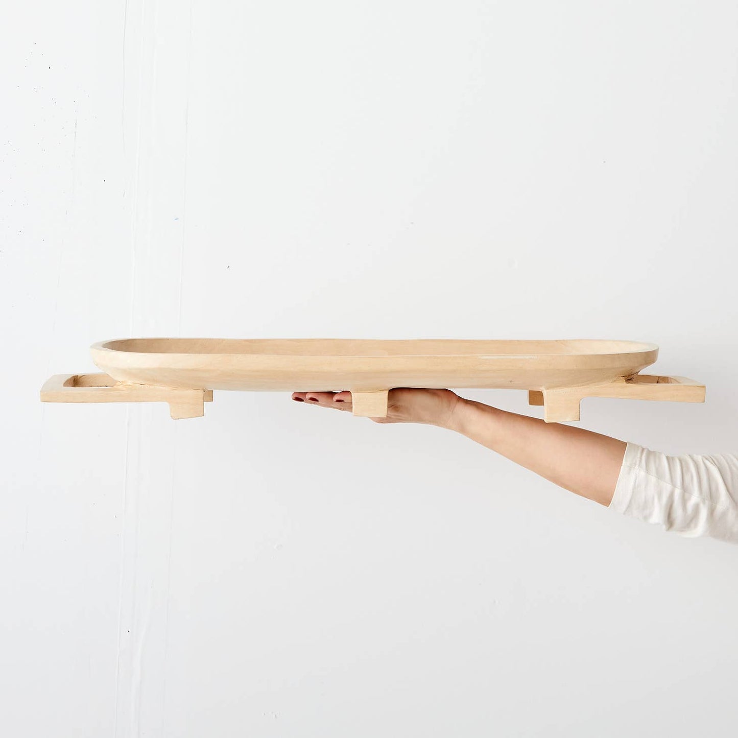 These elegant, raised long trays are hand carved in Eswatini from sustainably sourced Jacaranda wood, a form of rosewood that is very common throughout southeast Africa. They are carved from a single piece of wood, including the legs and handles, and polished to a natural sheen, available in a raw, light wood finish.