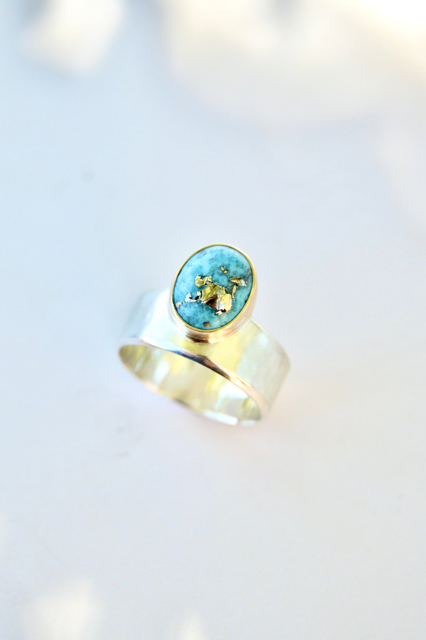 Made by hand in Northern New Mexico using recycled metals and responsibly sourced stones. This ring features a large cabochon Persian Turquoise stone set in a 14k yellow Gold bezel on a wide Sterling Silver band with matte finish. Mesa Ring by Halcyon Jewelry.