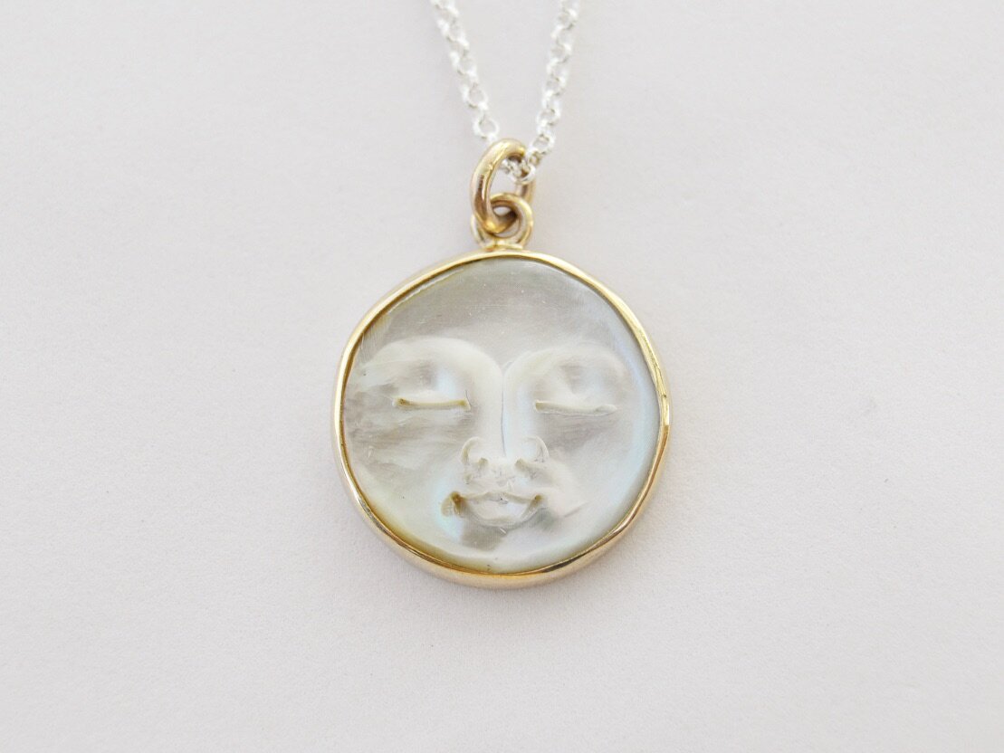 Made by hand in Northern New Mexico using recycled metals and responsibly sourced stones, this timeless, heirloom piece is sure to make a statement.  This ring features a carved Mother of Pearl moon set in a 14k yellow Gold bezel hung on a Sterling Silver chain. Lunarian necklace by Halycon Jewelry.