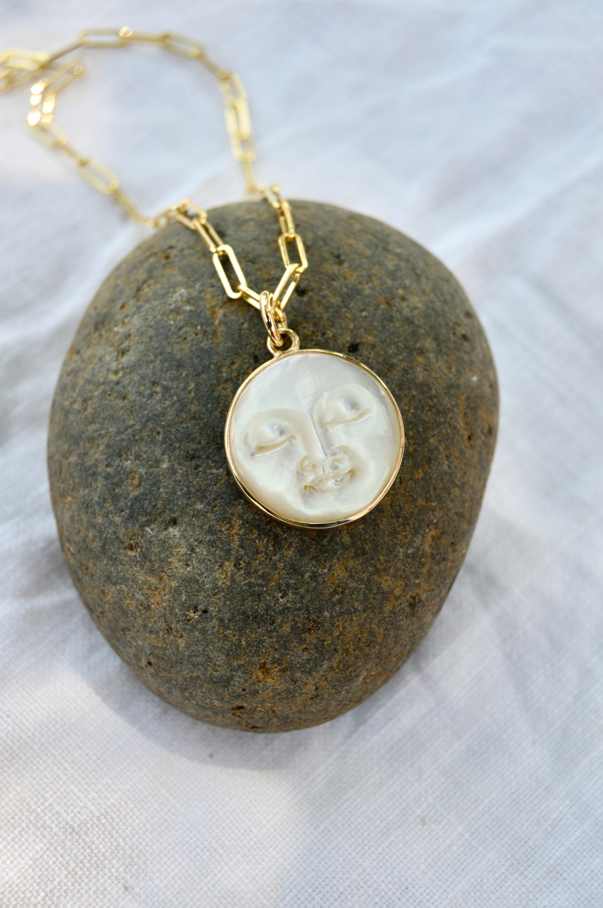 Made by hand in Northern New Mexico using recycled metals and responsibly sourced stones, this timeless, heirloom piece is sure to make a statement.  This ring features a carved Mother of Pearl moon set in a 14k yellow Gold bezel hung on a Sterling Silver chain. Lunarian necklace by Halycon Jewelry.