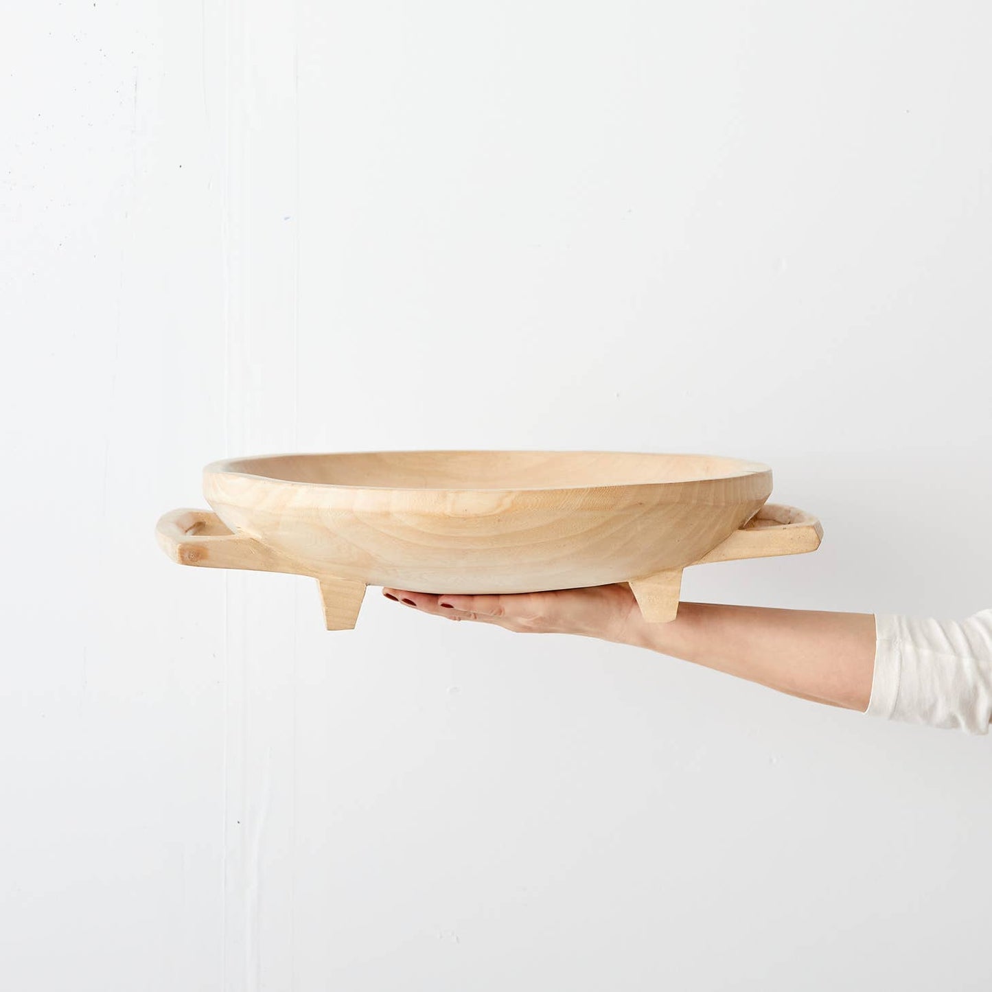 Raised, round platter hand-carved in Eswatini from sustainably-sourced Jacaranda wood, a form of rosewood that is very common in southeast Africa. Carved from a single piece of wood, including the legs and handles, and polished to a natural sheen. Available in a raw, light wood finish or a dark stain.
