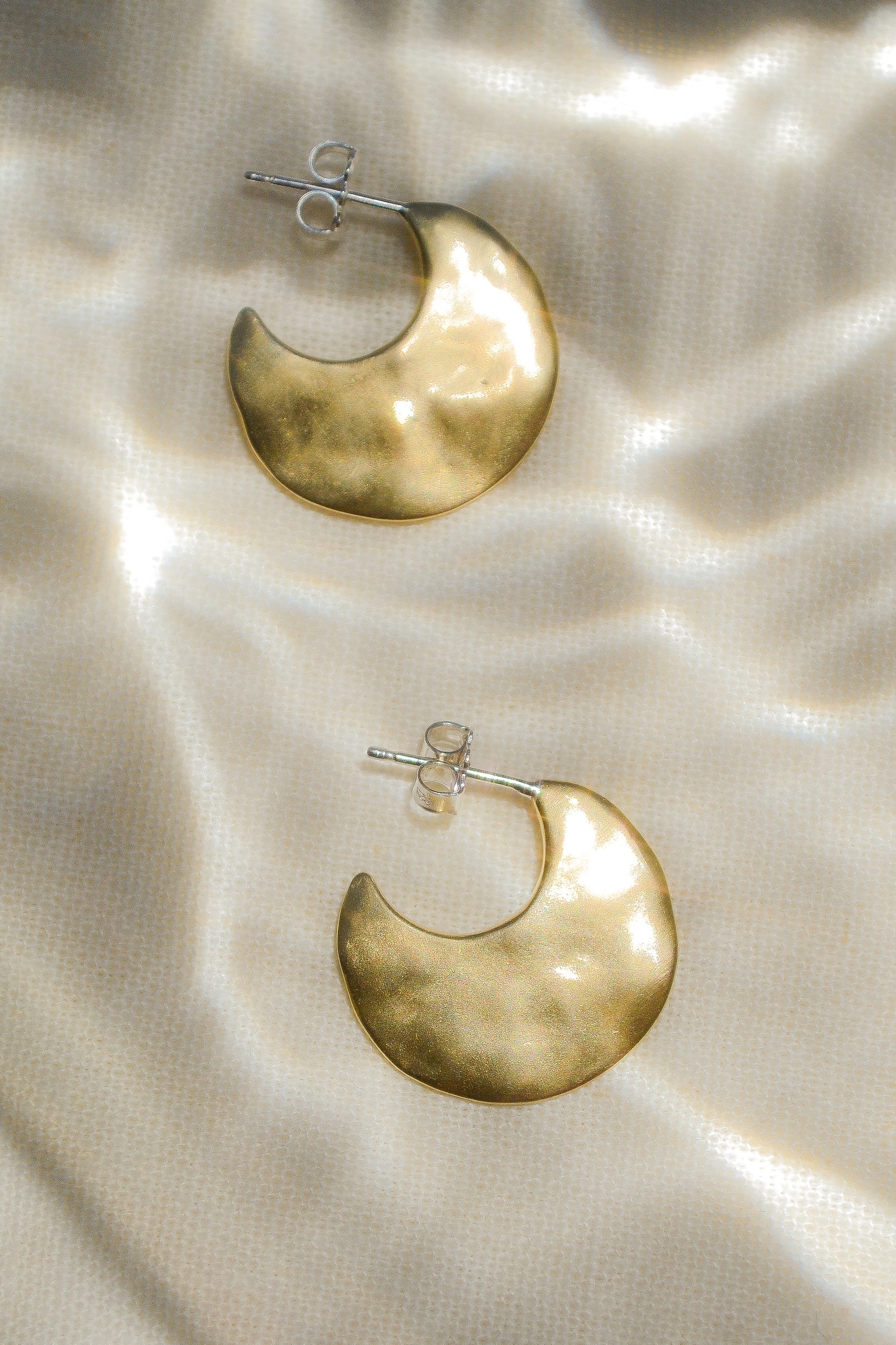 Bora Hoops by Amanda Hunt. A smooth yet slightly textured hoop. Light as a feather. Available in hand cast sterling silver with sterling silver posts or hand cast yellow bronze.
