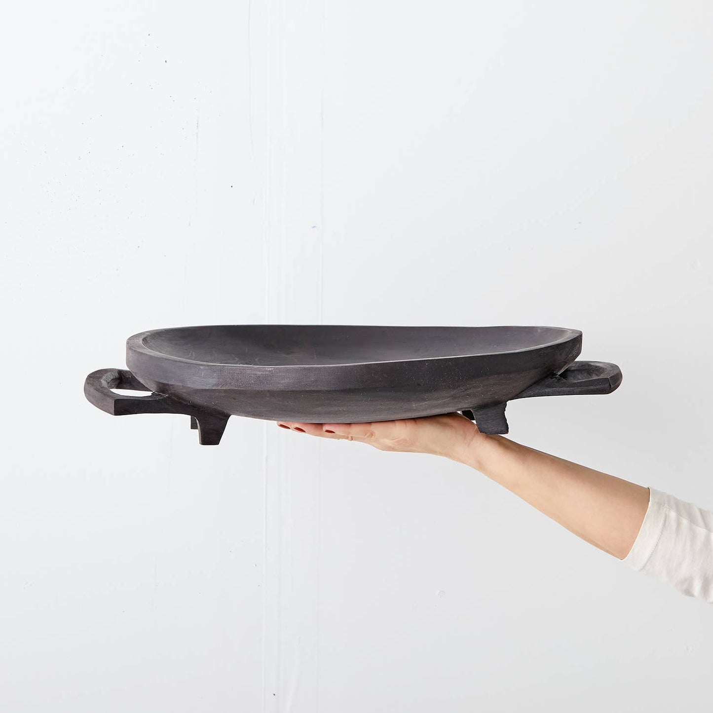 Raised, round platter hand-carved in Eswatini from sustainably-sourced Jacaranda wood, a form of rosewood that is very common in southeast Africa. Carved from a single piece of wood, including the legs and handles, and polished to a natural sheen. Available in a raw, light wood finish or a dark stain.