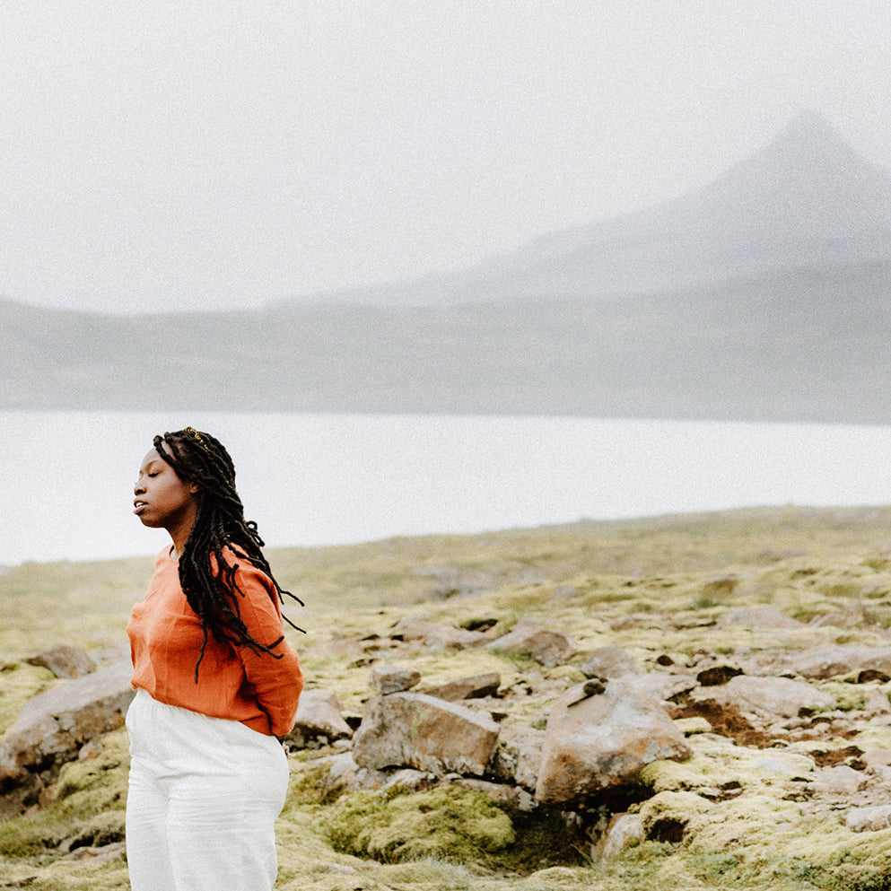 Ethically-and sustainably produced pants and linen top worn by a woman standing in front of an Iceland landscape