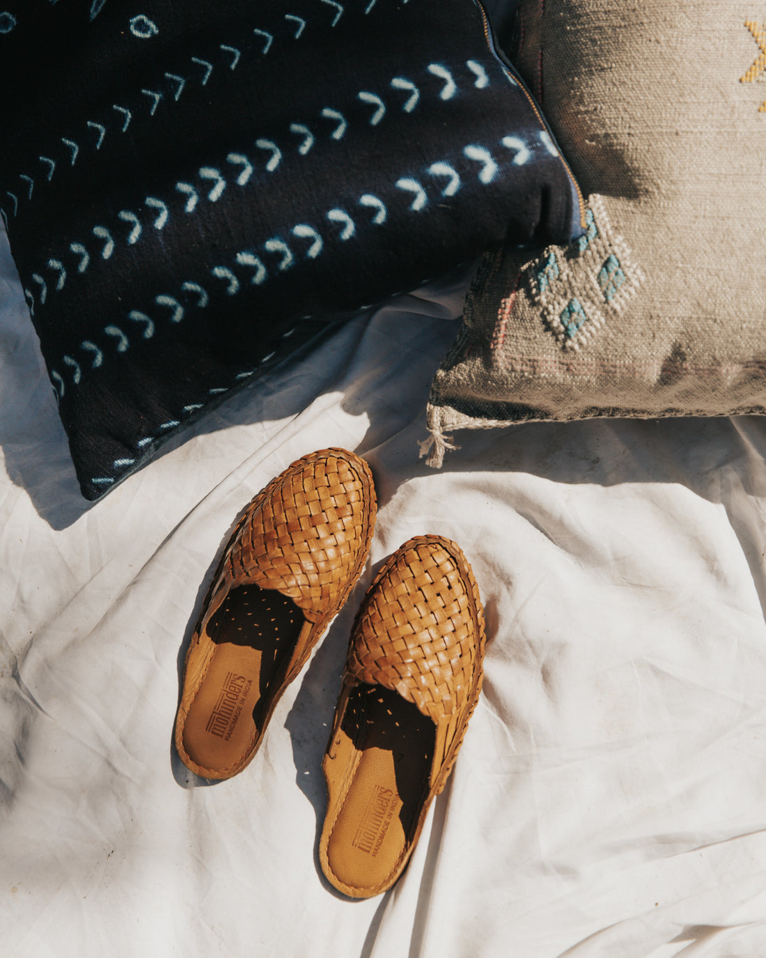 A pair of handwoven Mohinders rest near handmade and fair trade bogolan and cactus silk Moroccan pillows