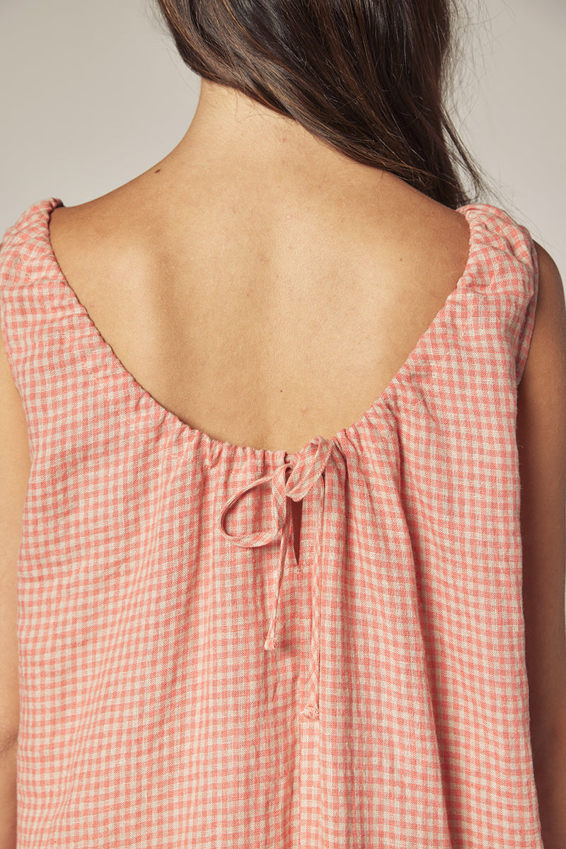 The back of a woman wearing a sustainably-made gingham cotton dress in a pink check