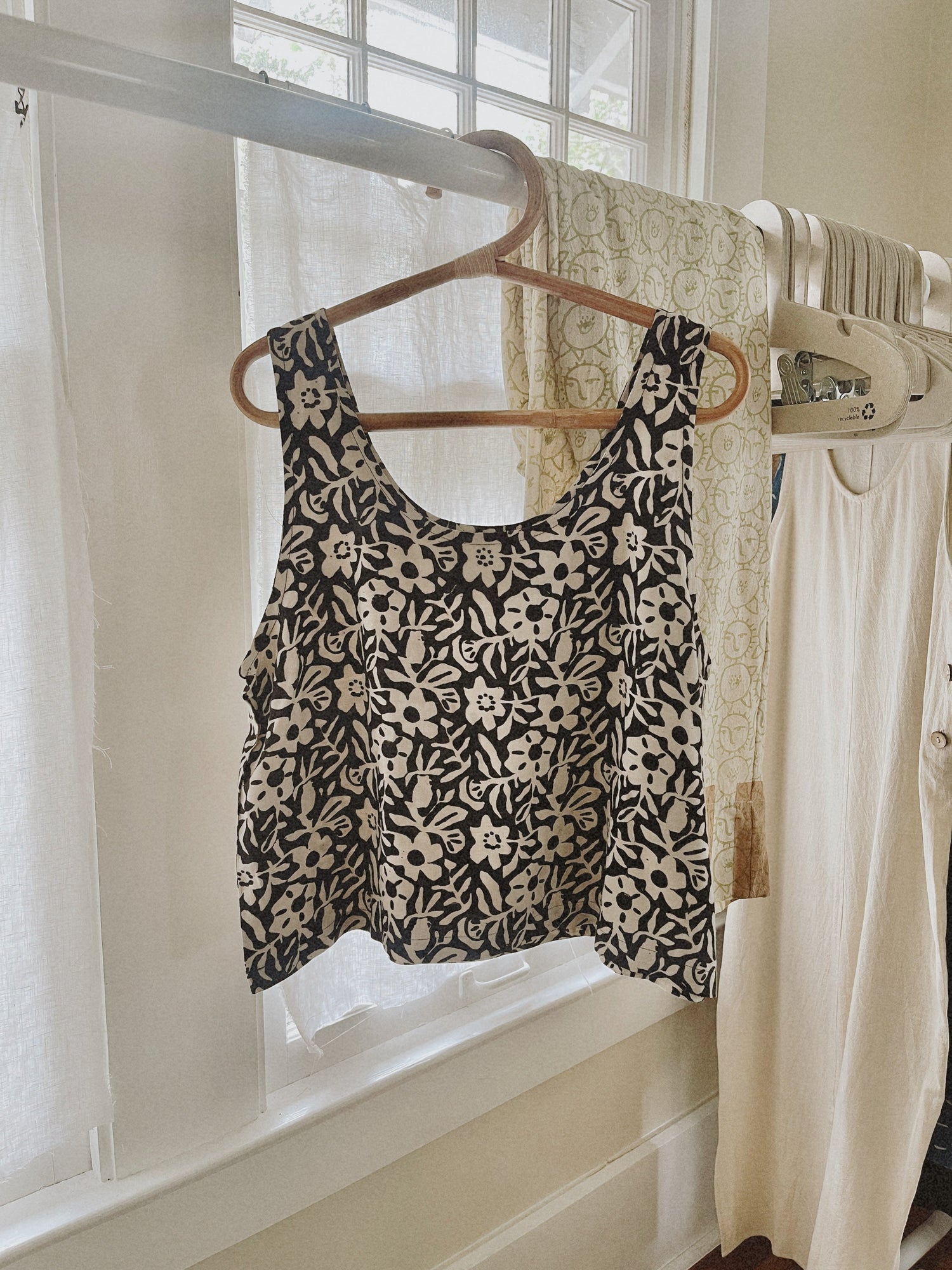 PO-EM hand block-printed tank top made ethically and sustainably, hanging on a hanger near a light-filled window