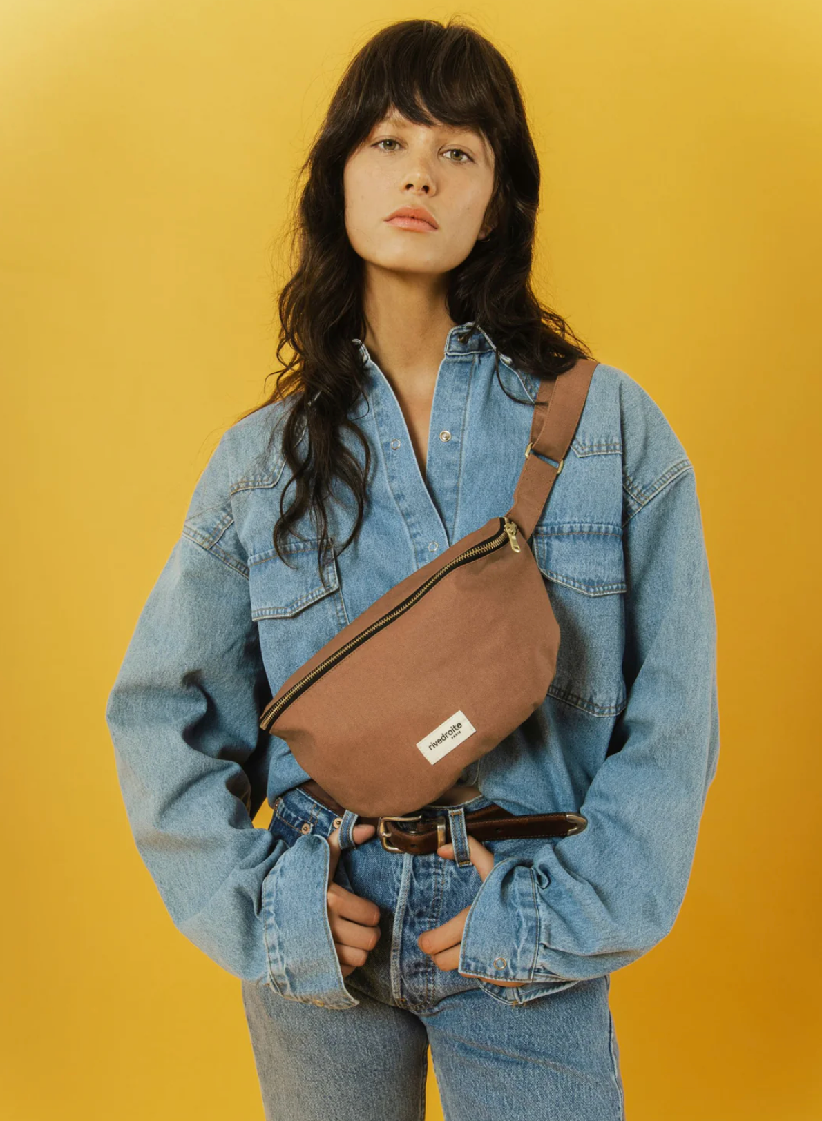 Woman wearing a denim jacket and rivedroite waxed canvas sling bag from Paris