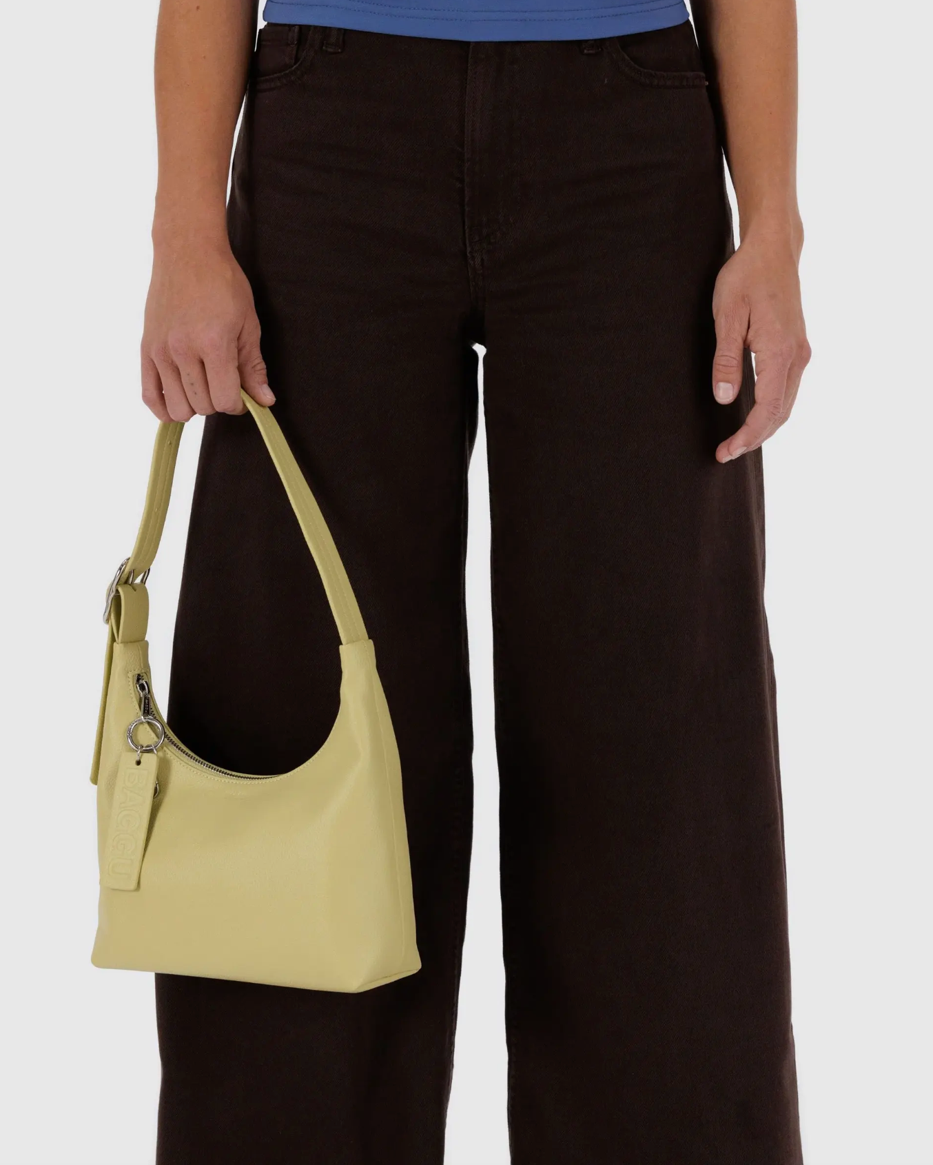 Woman wearing sustainable denim jeans holds an up cycled leather purse by Baggu