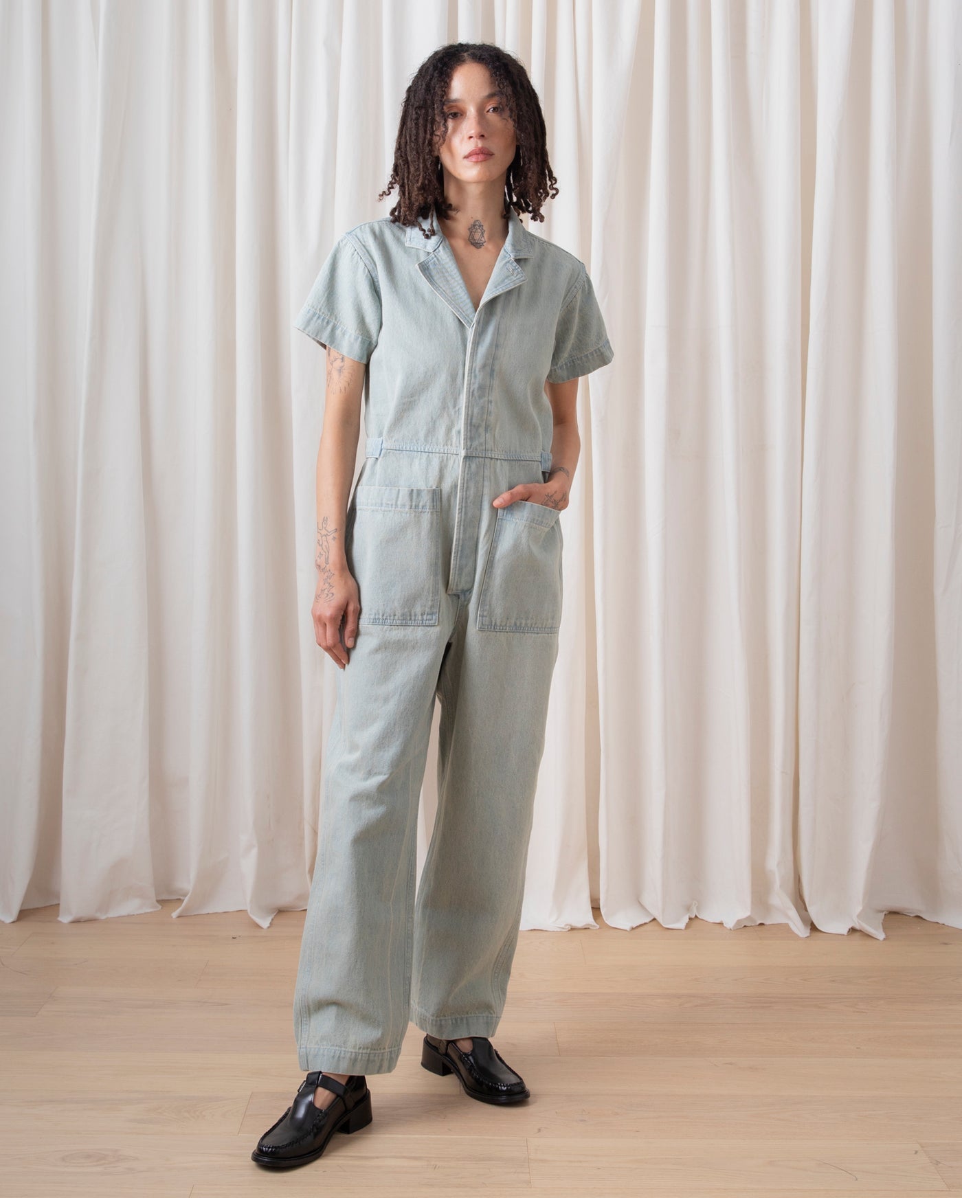 Ali Golden denim boiler suit on sale now - worn by a woman with her hand in her pocket who dresses ethically
