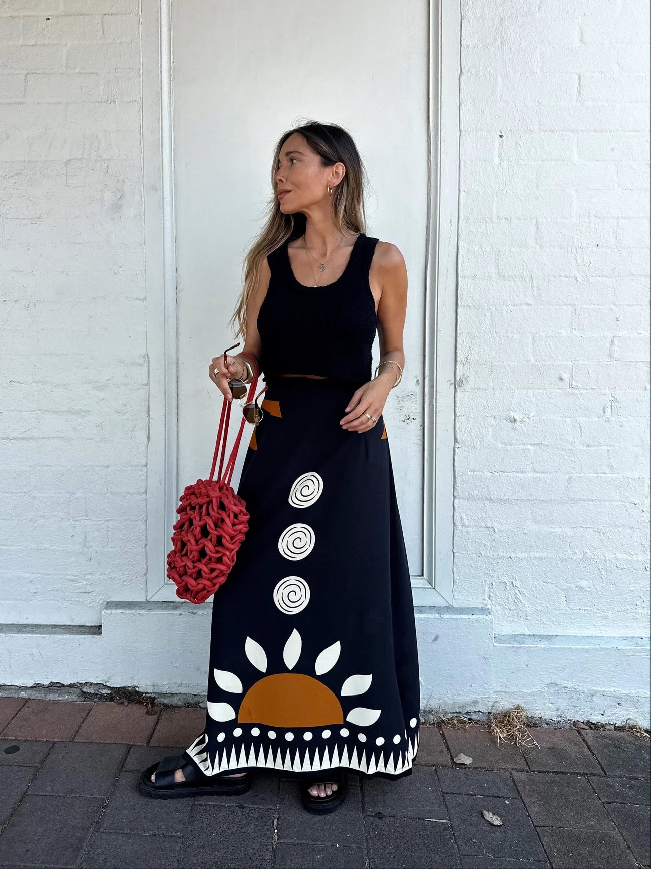 Woman wears Ottway brand black knit tank and printed skirt made sustainably