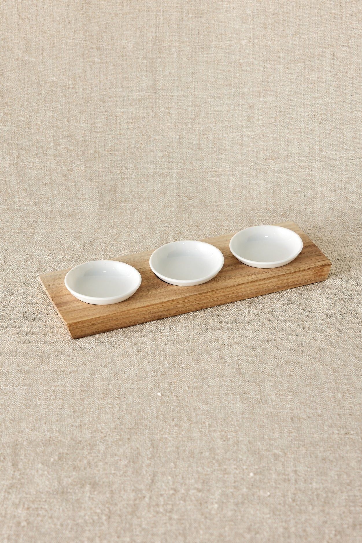 Crafted with a wooden base and three exquisite white ceramic bowls, this set seamlessly complements any home décor. Elevate your gatherings with this versatile set, ideal for presenting sauces, spices, or delightful little snacks. Handmade in South Africa.