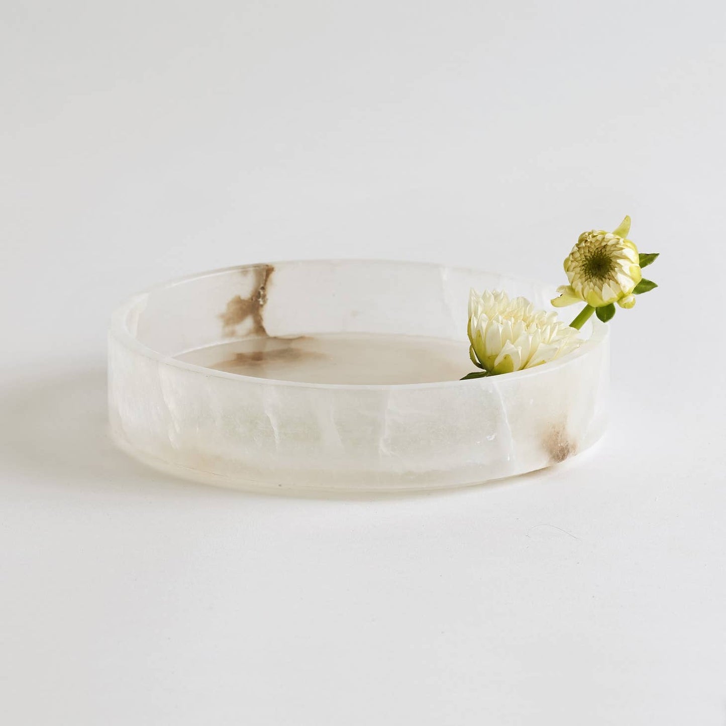 Handcrafted from fine Portuguese alabaster, this chic round tray will add a spa feel to your bath or bedroom.  A hand-polished finish accentuates natural color variations in the stone, making each tray unique. A stable, footed base and vertical rim safely contain & stylishly display its contents.