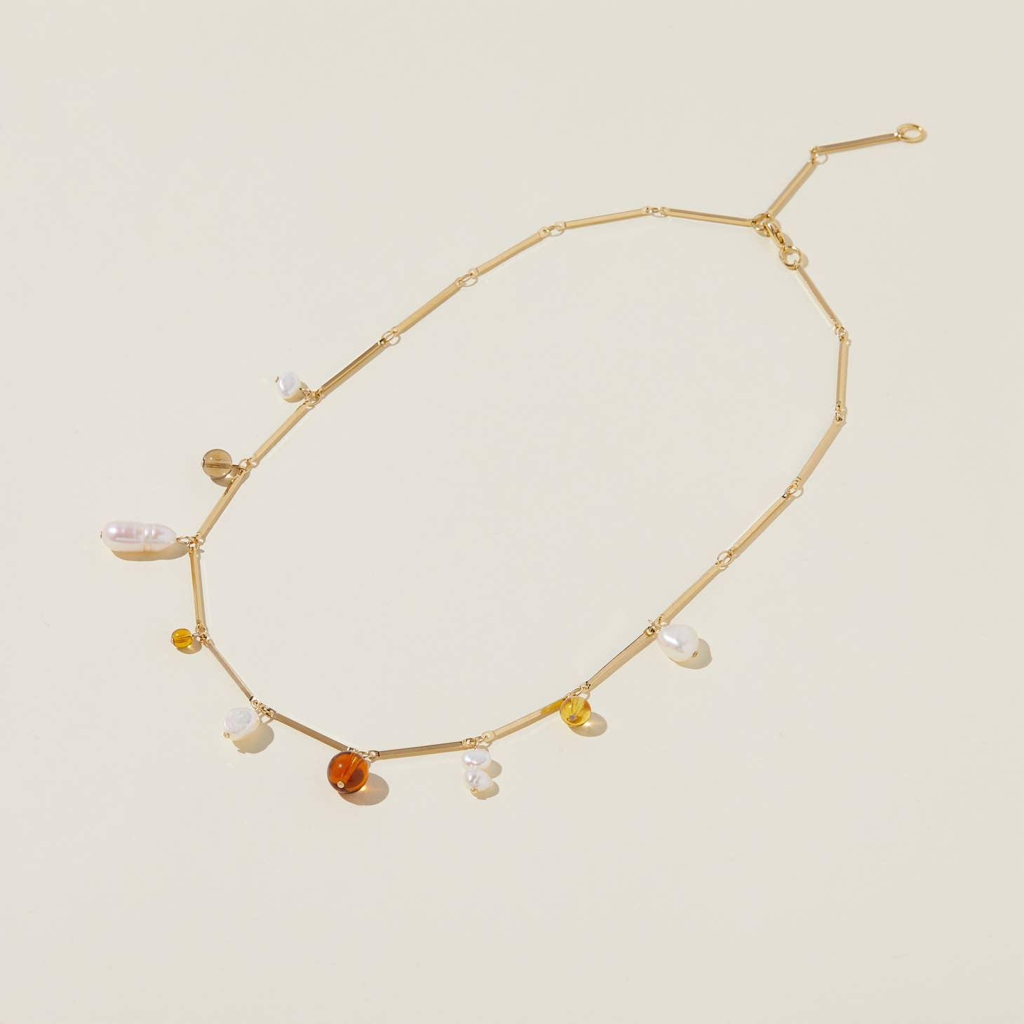 Sophisticated yet playful, freeform pearls and translucent glass dangle from a modern gold plated brass bar chain. 
