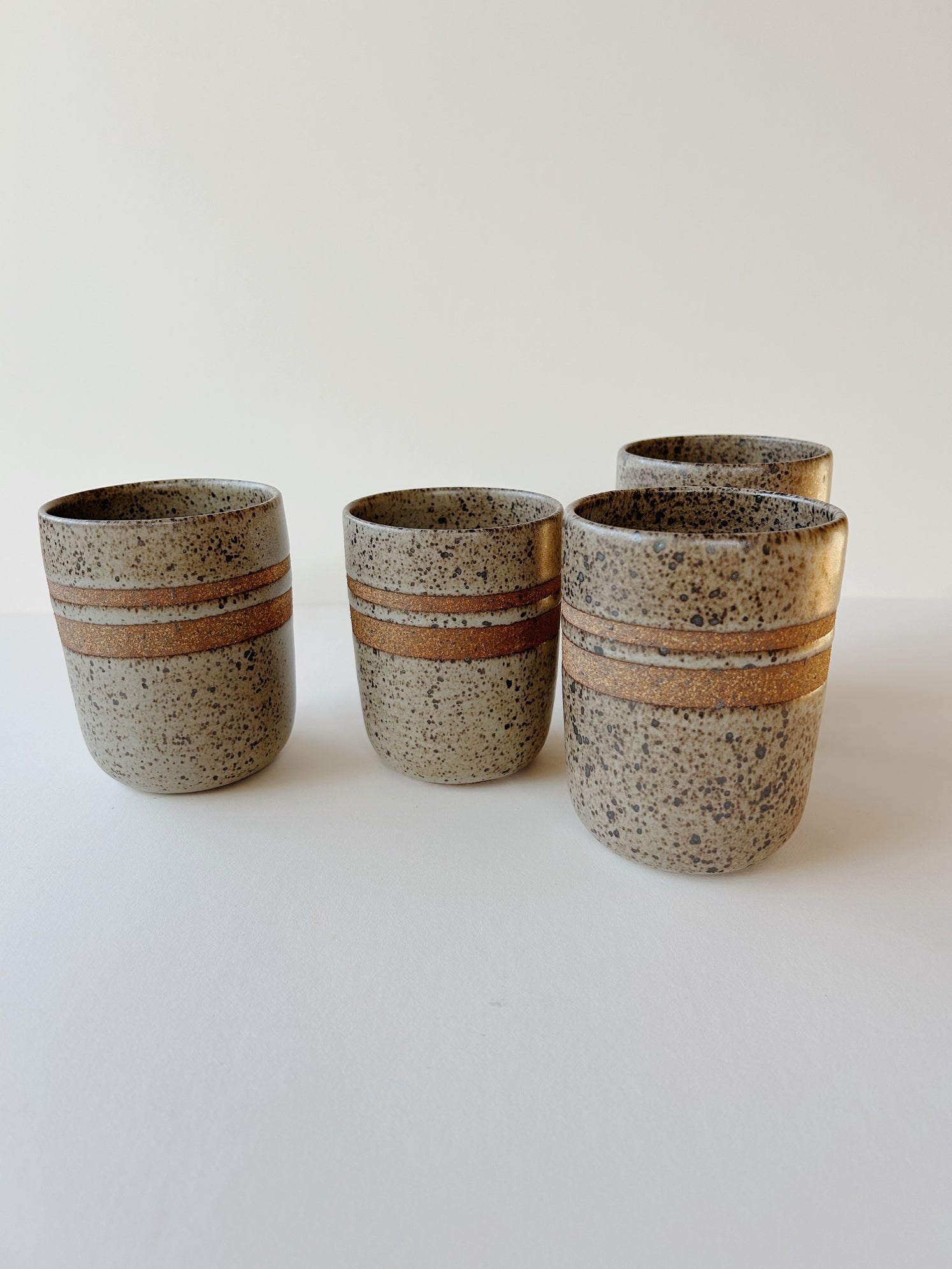 A matte grey and speckled ceramic tumbler cup with raw clay rings for a nice hand grip.  Made-by-hand, by Lisa Fontaine in her home studio in Berkeley. CA.
