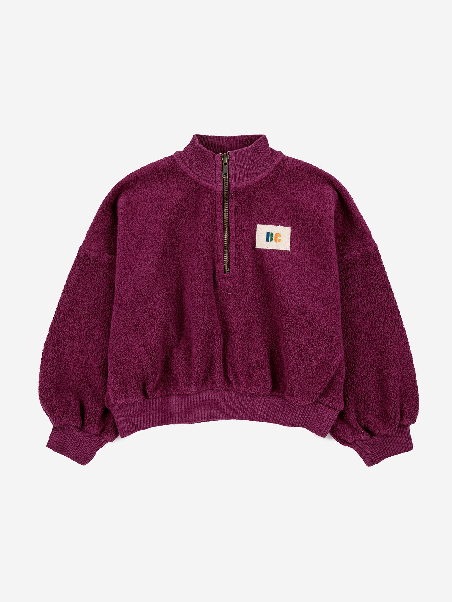 B.C. Label Sweatshirt by Bobo Choses. 100% organic cotton purple fleece sweatshirt. Designed with balloon sleeves, dropped shoulder, ribbed mock neck & hems, and a half zipper. It has a loose fit.  Made ethically and sustainably in Portugal for Bobo Choses.