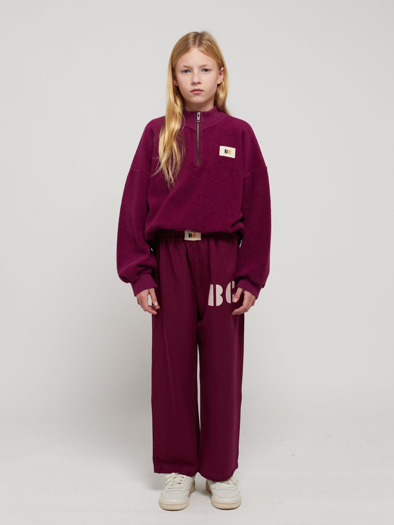 B.C. Label Sweatshirt by Bobo Choses. 100% organic cotton purple fleece sweatshirt. Designed with balloon sleeves, dropped shoulder, ribbed mock neck & hems, and a half zipper. It has a loose fit. Made ethically and sustainably in Portugal for Bobo Choses.