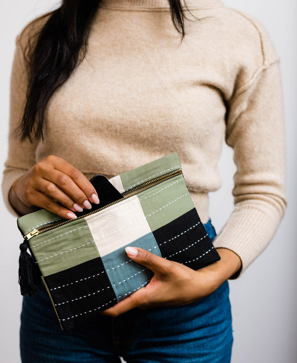 This beautiful contemporary pouch complete with a tassel zipper pull, features a color block checkered design and charming stitch details. Made with organic cotton, use it to stay organized, store makeup, a cell phone, or important receipts.