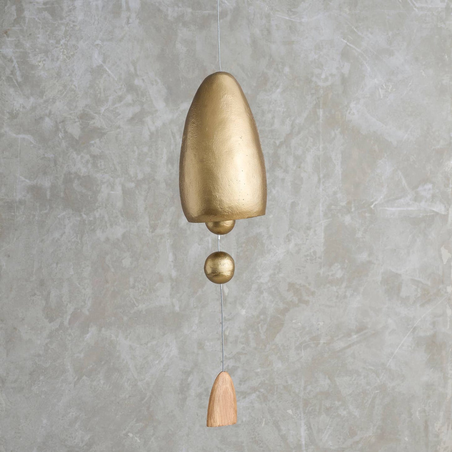 This tall, cone-shaped bell is sand-cast in aluminum and given an antique brass finish, then outfitted with a pair of hollow metal spheres and a dome-shaped, polished oak sail on its center cord. Ethically made in India.