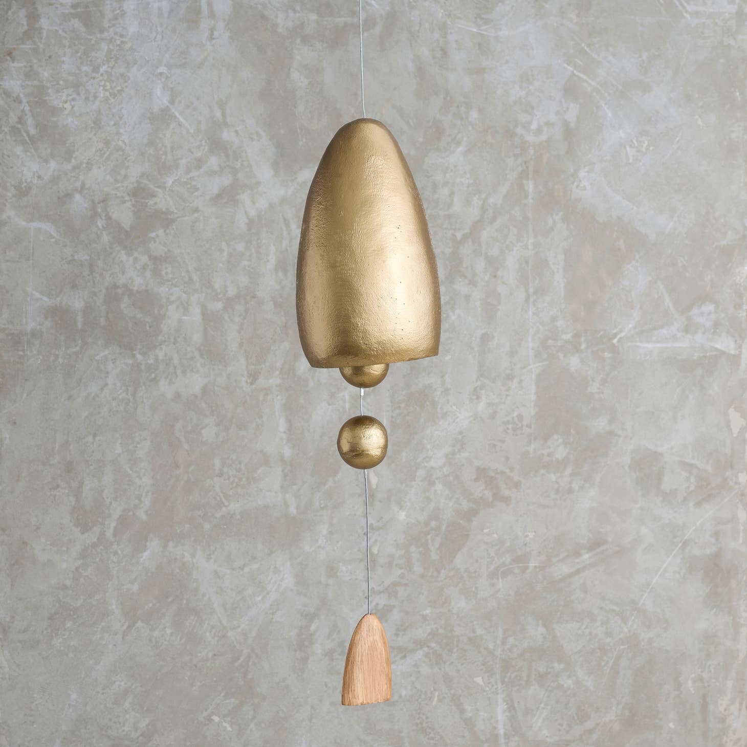This tall, cone-shaped bell is sand-cast in aluminum and given an antique brass finish, then outfitted with a pair of hollow metal spheres and a dome-shaped, polished oak sail on its center cord. Ethically made in India.