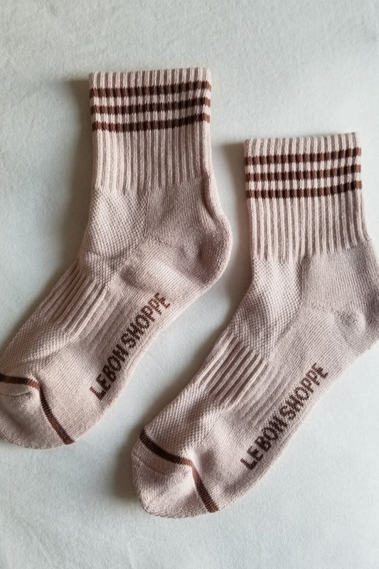 Pair of light pink socks with brown checkered bands on a light gray background