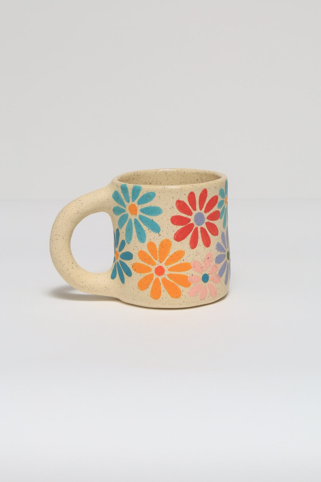 Handmade ceramic mug featuring a hand painted flower design in colorful underglaze. melville ceramics