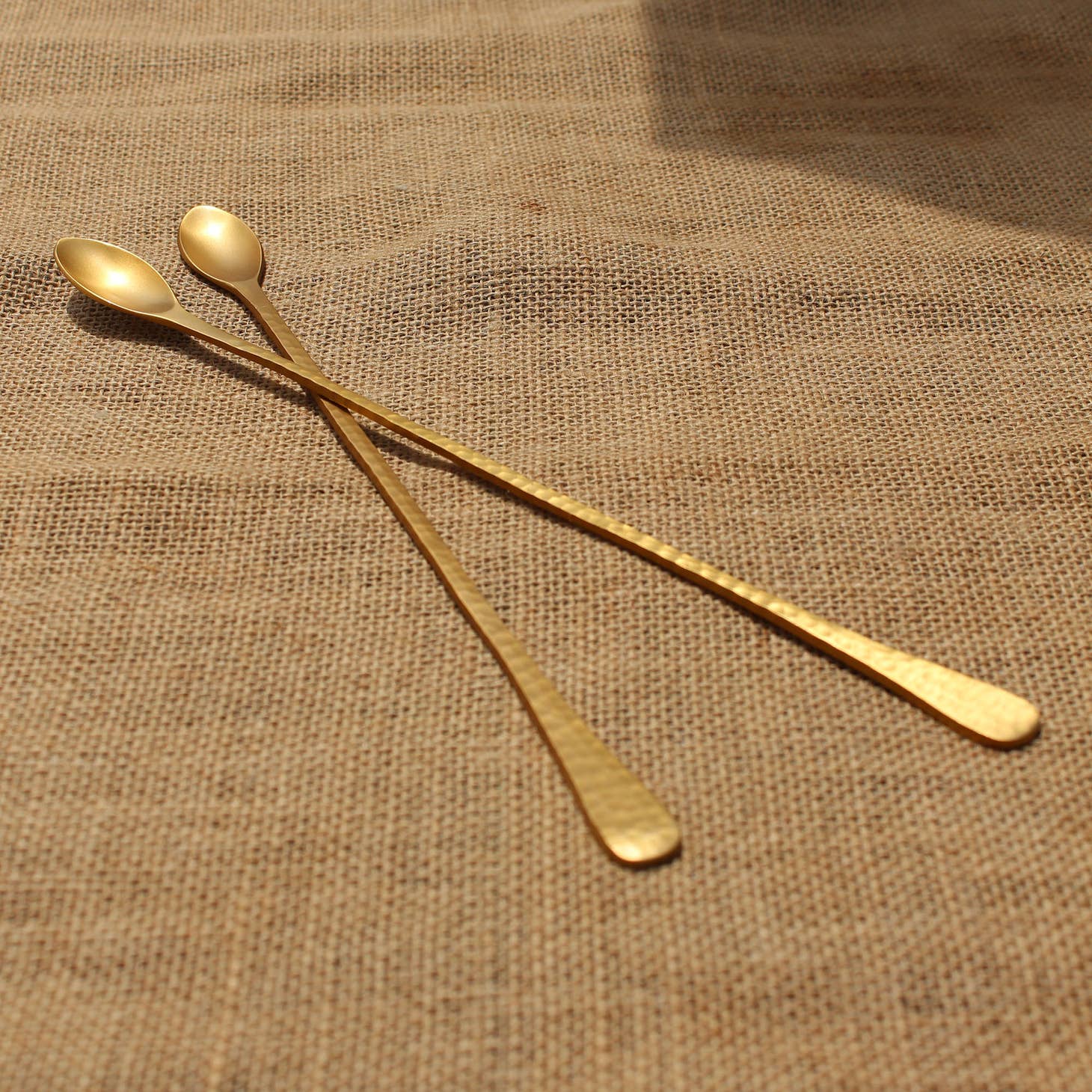 Long brass bar spoons bring modern flair to your bar with their elongated silhouettes, gently hammered texture and matte golden hue.  Use them in your tallest glassware and pitchers to guarantee no ingredient gets left behind. the collective pebbled long spoon
