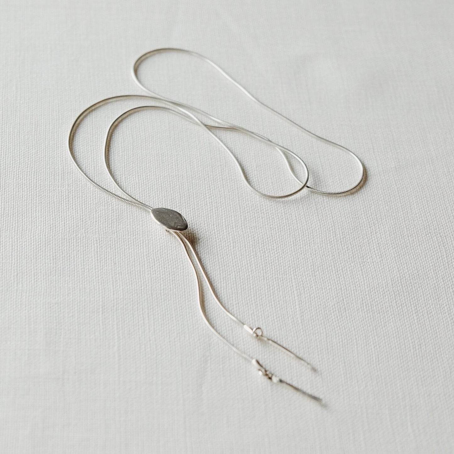 ascent sterling silver bolo tie / An understated but sexy little necklace. Tiny oval charm slides like a bolo tie with two hammered drops at the ends.   Handmade by Sarah Safavi.