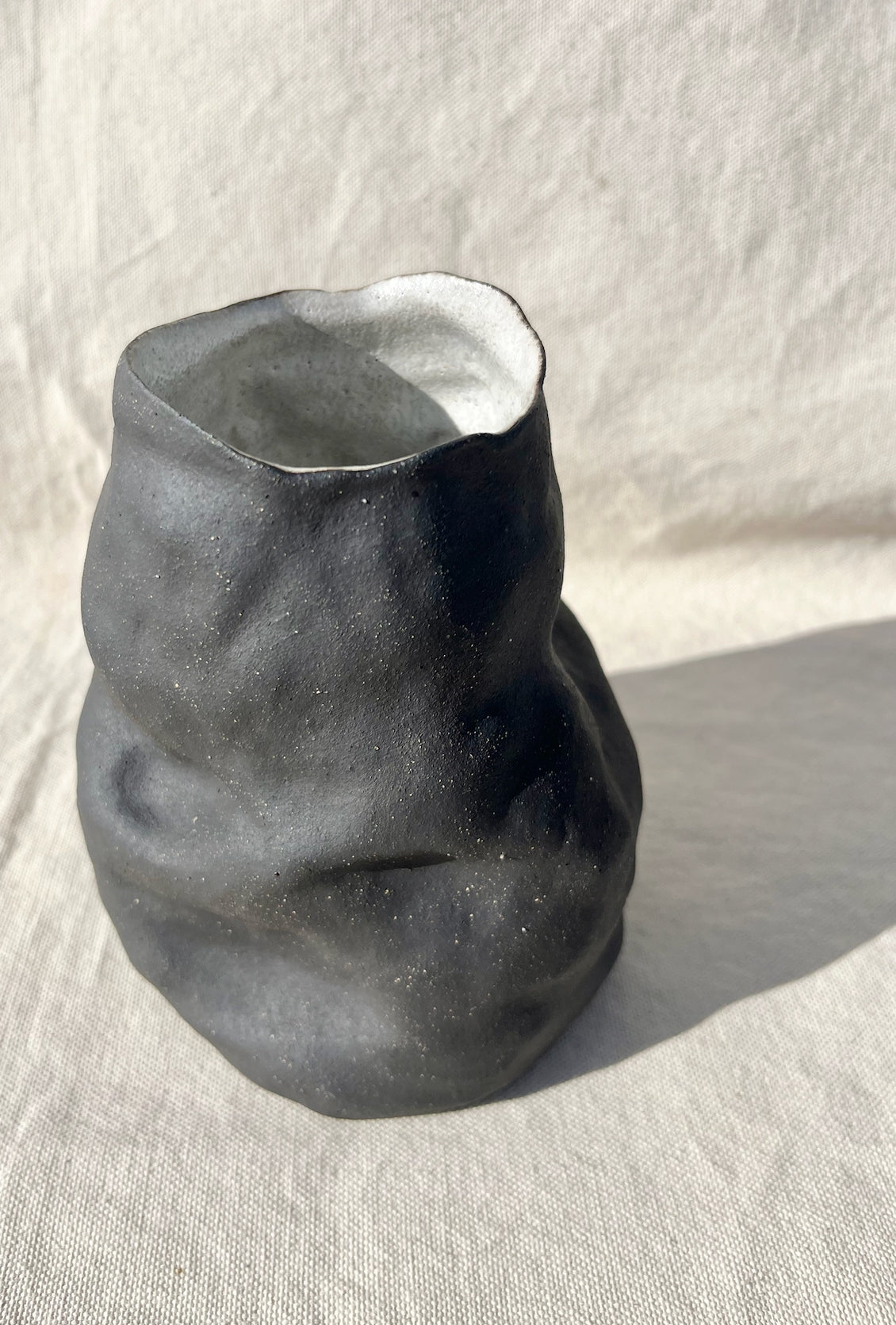 Organic vase with a black and white speckled clay body and white inside glaze. Hand built, glazed and fired in Slo, Ca.