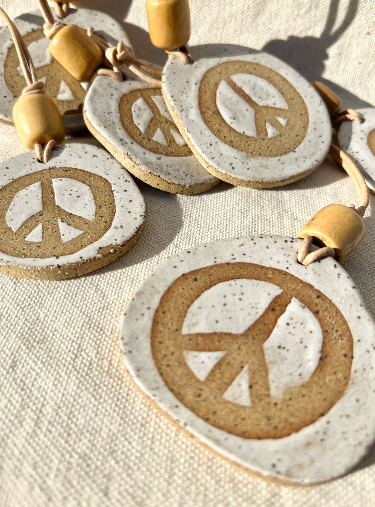 Add a hint of peace to your space with these peace offerings. Speckled clay peace signs adorned with a vintage wooden bead and leather cord. Hand built, glazed and fired in SLO, Ca.