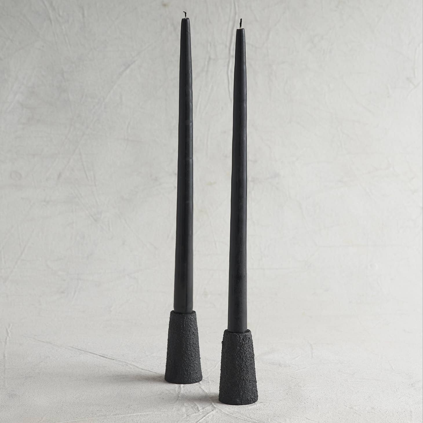 Thick, sand-cast aluminum forms are finished in a heavy, ash black textured coating, giving them a lava-like appearance. These taper holders fit the standard (7/8" diameter) candles and are backed with felt to prevent surface scratches. Made in India.