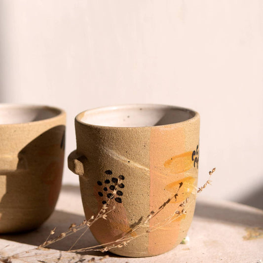 Sleek tumbler featuring a ledge halfway round.  Perfect for small drinks and small hands.  Raw stoneware finished with handpainted embellishments & white glazed interior. Handmade in Denver, CO.