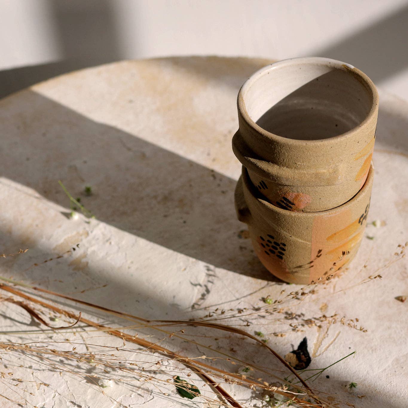 Sleek tumbler featuring a ledge halfway round.  Perfect for small drinks and small hands.  Raw stoneware finished with handpainted embellishments & white glazed interior. Handmade in Denver, CO.