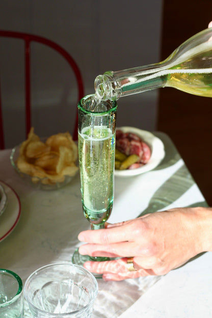 A playful champagne flute with a unique silhouette, designed to keep the party going. Each glass is handmade from recycled glass by artisan partners in Bogotá, Colombia, giving every piece its own subtle character.