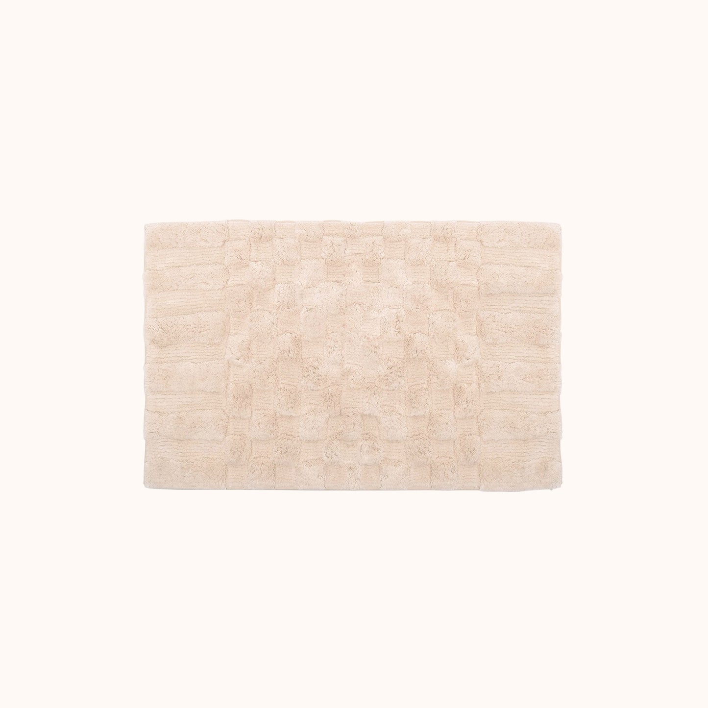 The Clea Bath Mat is a soft, neutral blush hue with a subtle check pattern created by contrasting shag heights. This bath mat is perfect for adding just a hint of color and texture. Ethically produced and hand made in India.